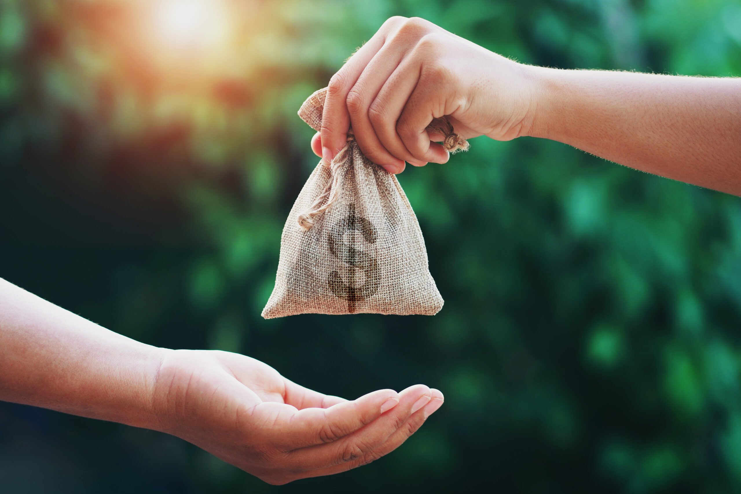 hand giving money bag to another people on green background with Rolling a 529 into a Roth IRA